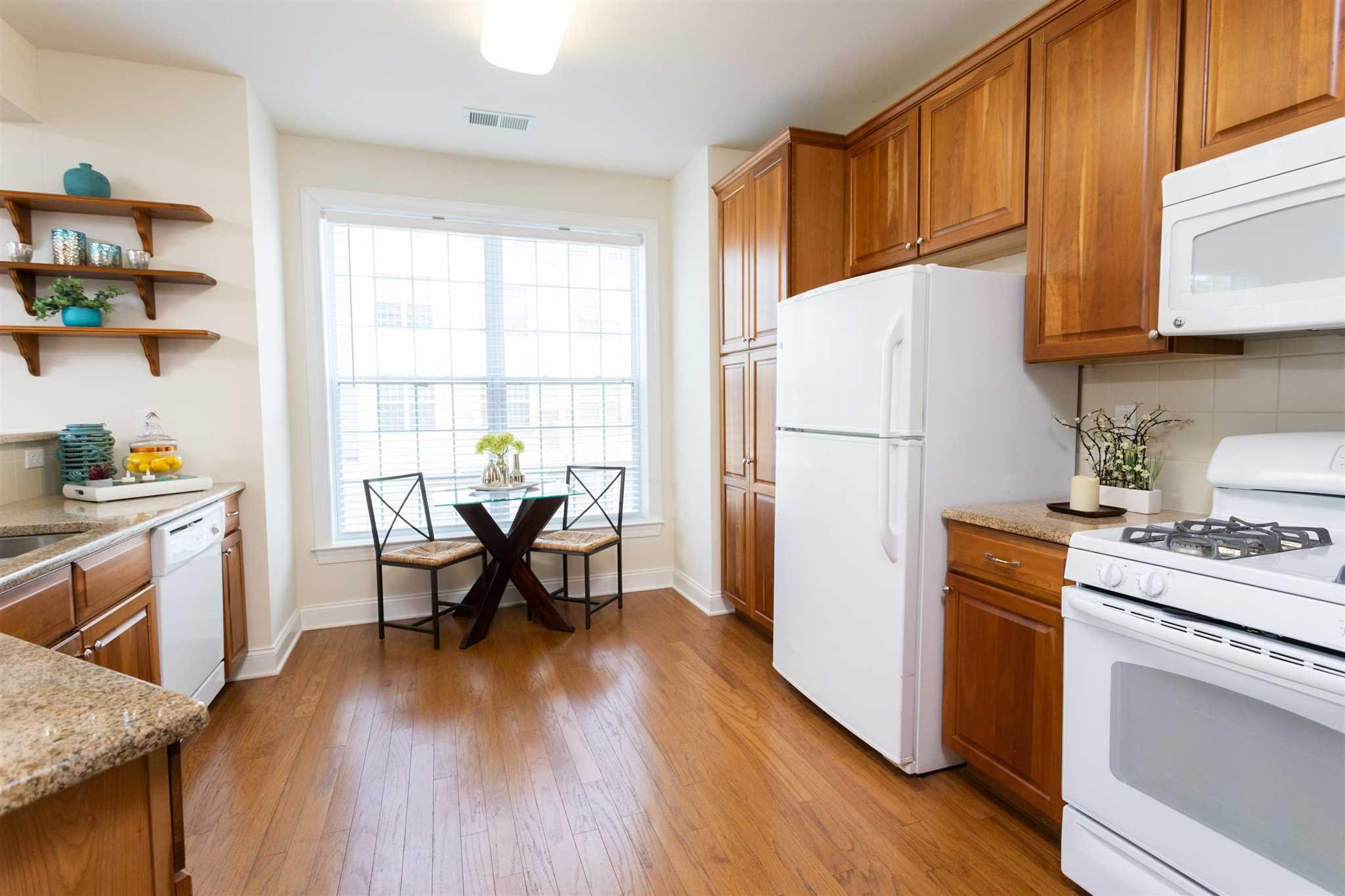 224 Regency Drive, Unit 224 Fishkill, NY 12524 - Photo 11 of 30 a kitchen with a refrigerator a stove a sink dishwasher and a dining table with wooden floor