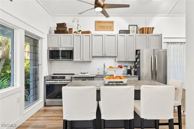 a white kitchen with stainless steel appliances granite countertop a stove a sink dishwasher and white cabinets with wooden floor