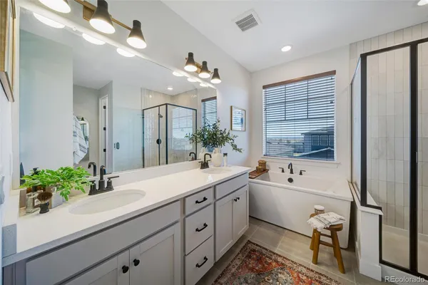 a spacious en suite bathroom with a double vanity sink a large mirror and a bathtub