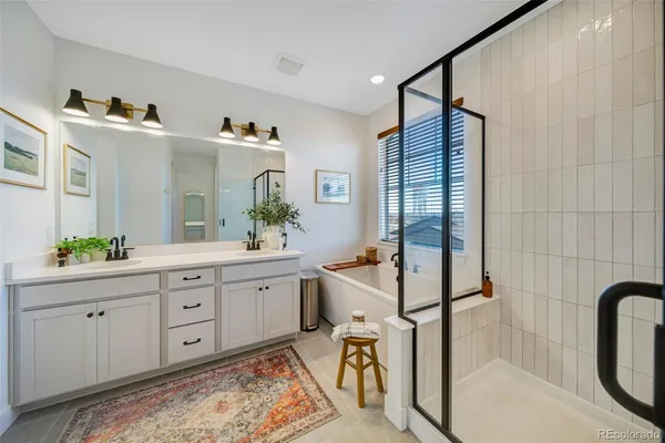 a spacious bathroom with a double vanity sink a mirror a bathtub and a shower