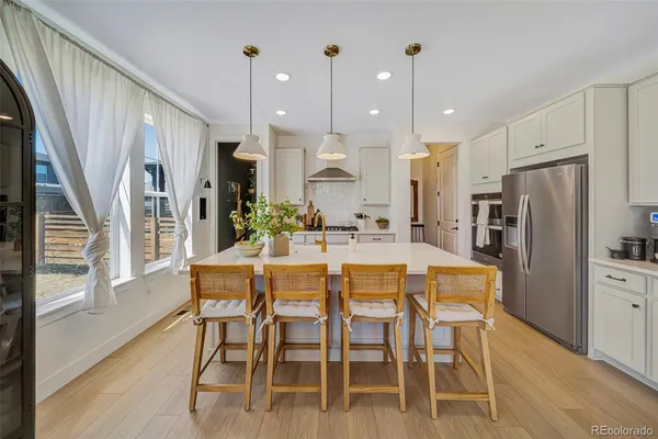 a kitchen with stainless steel appliances kitchen island granite countertop a refrigerator a stove a kitchen island with a dining table and chairs