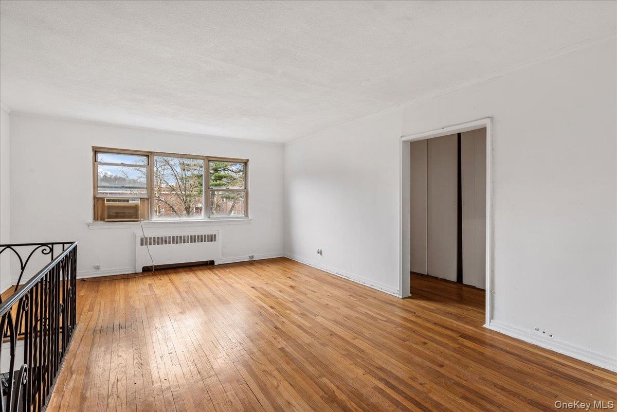87-24 Marengo Street, Unit 2B Queens, NY 11423 - Photo 9 of 22 an empty room with wooden floor and windows