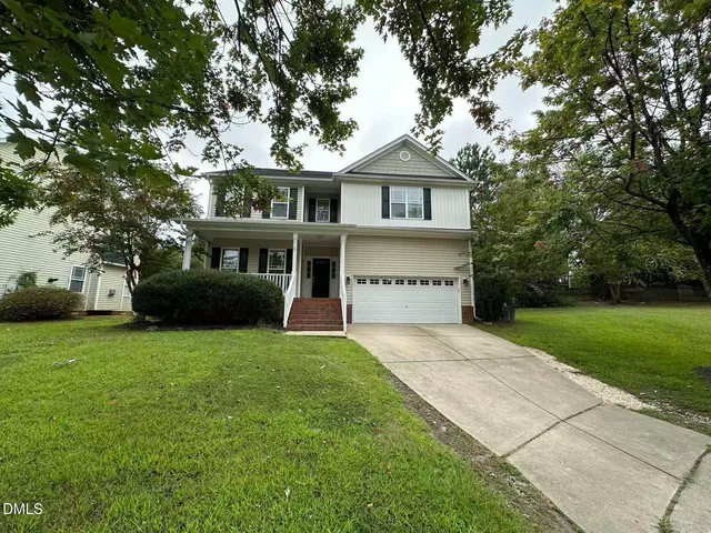 a front view of a house with a yard and trees