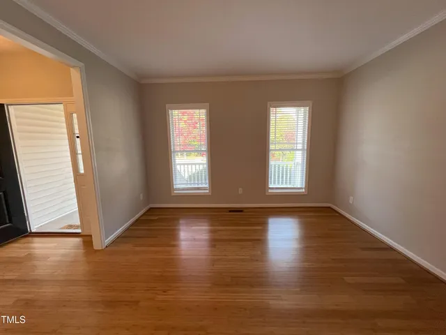 an empty room with wooden floor and windows with curtains view