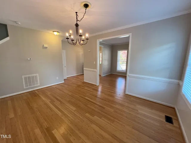 a view of empty room with wooden floor and kitchen view