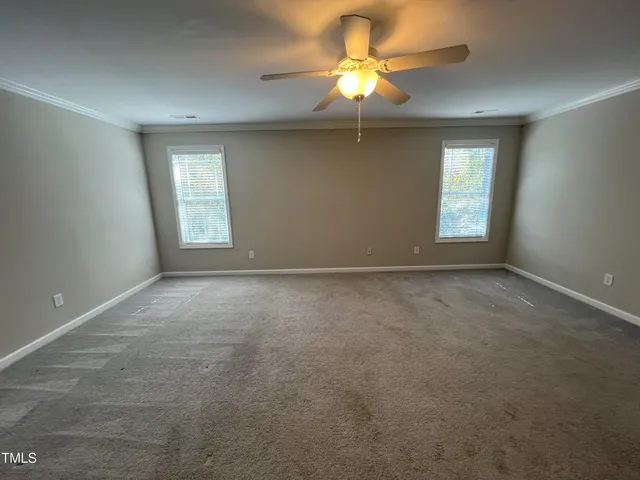 an empty room with a chandelier fan and windows