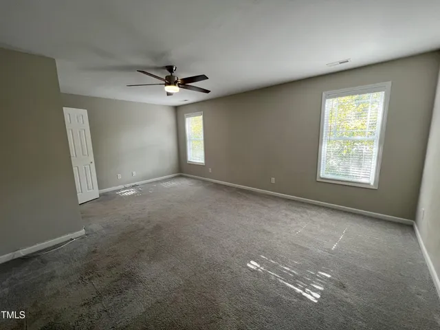 an empty room with windows and ceiling fan