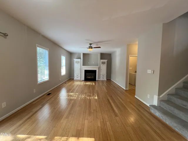 a view of empty room with wooden floor and fireplace