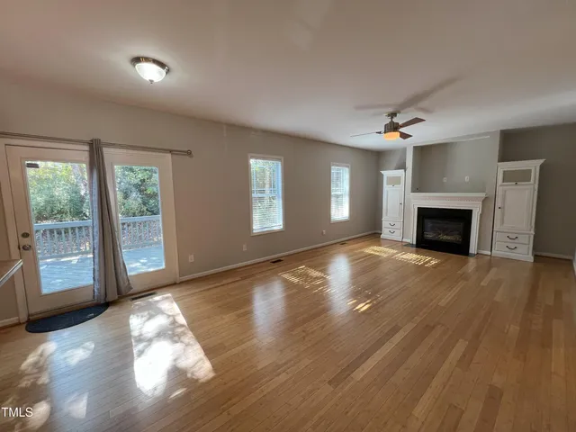 a view of a livingroom with a fireplace window and wooden floor