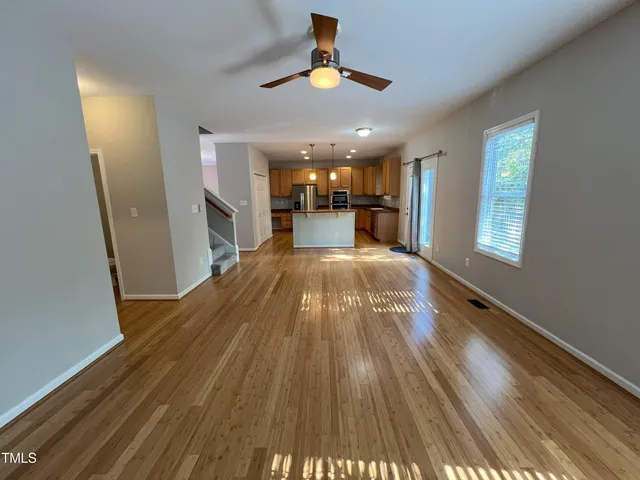 a view of a room with wooden floor ceiling fan and windows