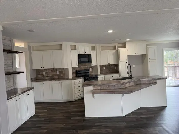 a kitchen with granite countertop white cabinets and stainless steel appliances