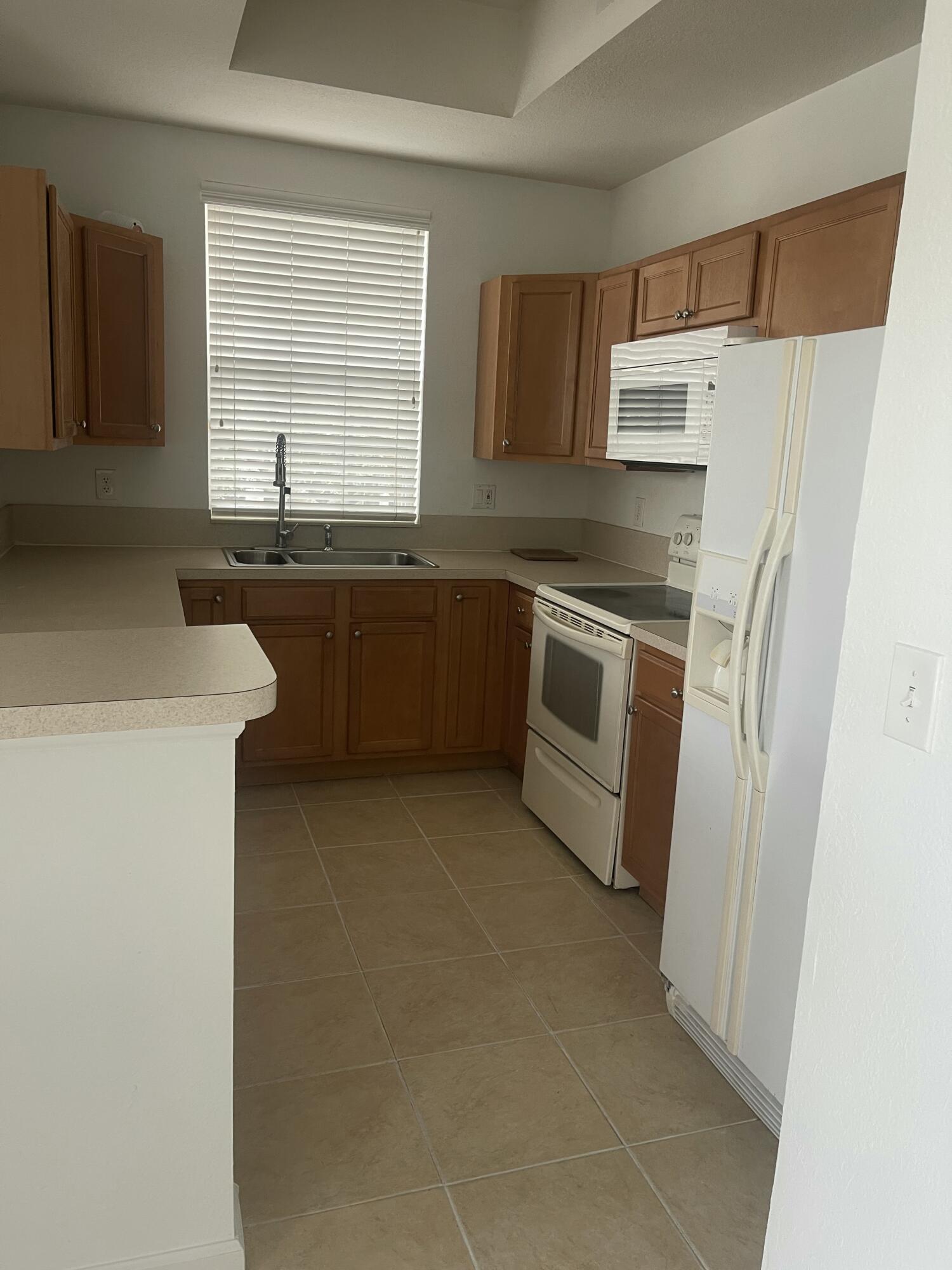 10440 Southwest Stephanie Way, Unit 211 Port St. Lucie, FL 34987 - Photo 2 of 13 a kitchen with stainless steel appliances granite countertop a sink stove and refrigerator