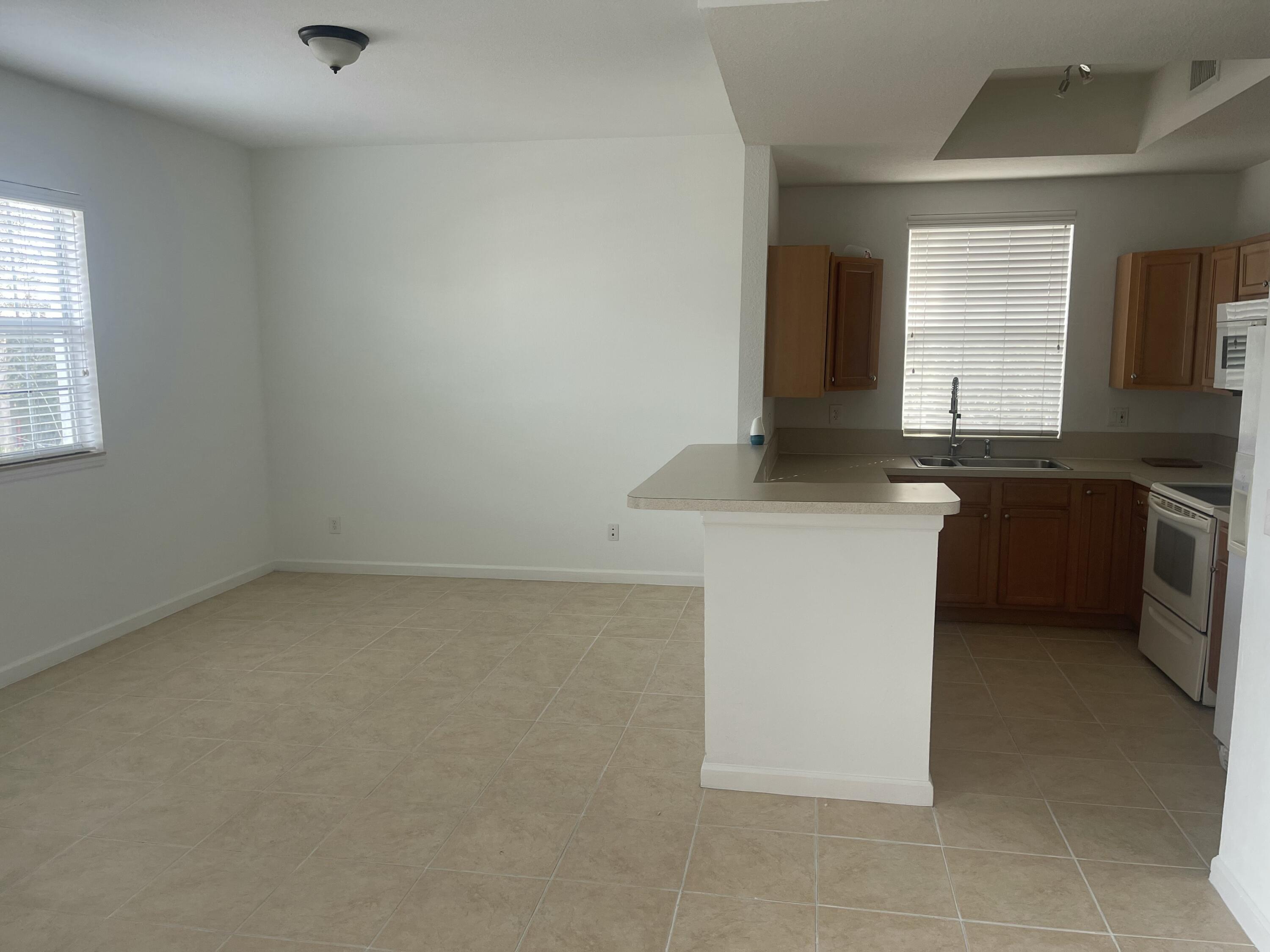 10440 Southwest Stephanie Way, Unit 211 Port St. Lucie, FL 34987 - Photo 3 of 13 a kitchen with a sink cabinets and window