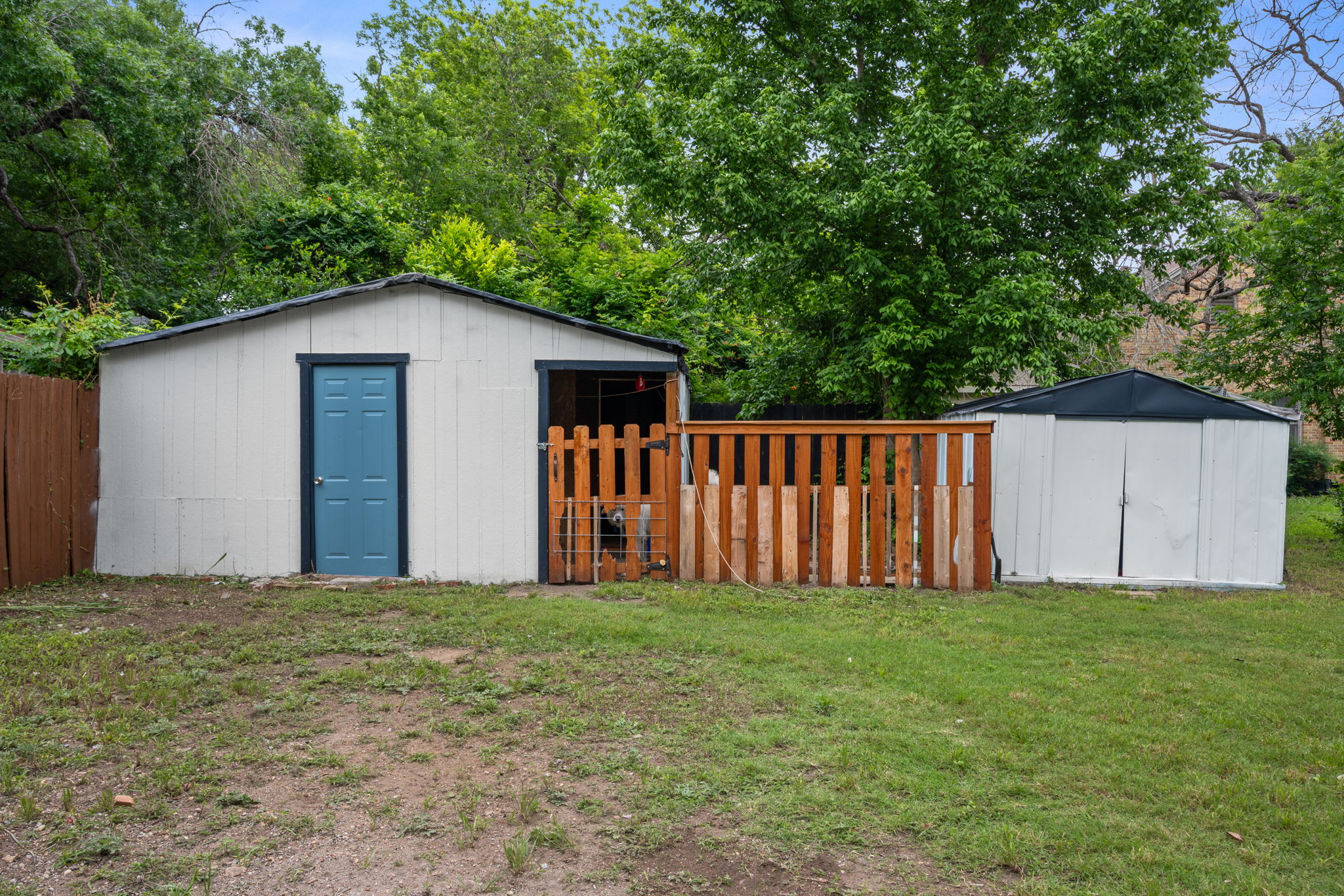 602 East 6th Street Cameron, TX 76520 - Photo 37 of 40 Rear yard featuring two storage sheds, one with a blue door and adjacent wood fencing