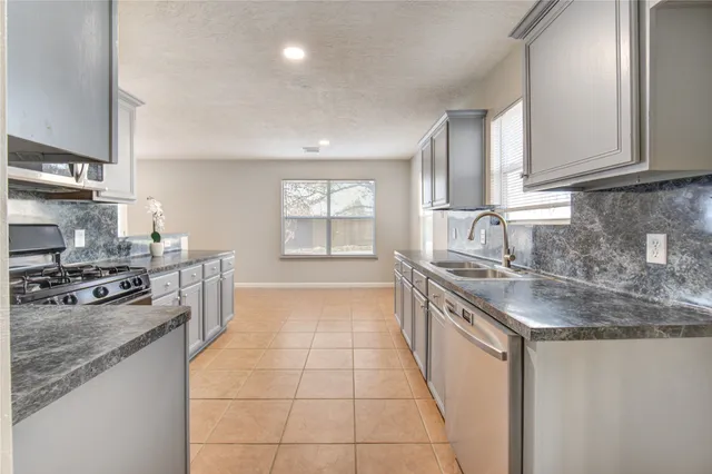 a kitchen with granite countertop a sink a counter top space appliances and cabinets