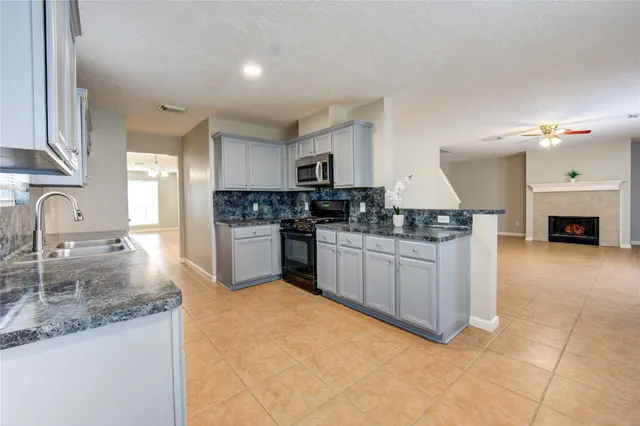 a kitchen with granite countertop a sink a stove top oven a counter space and cabinets