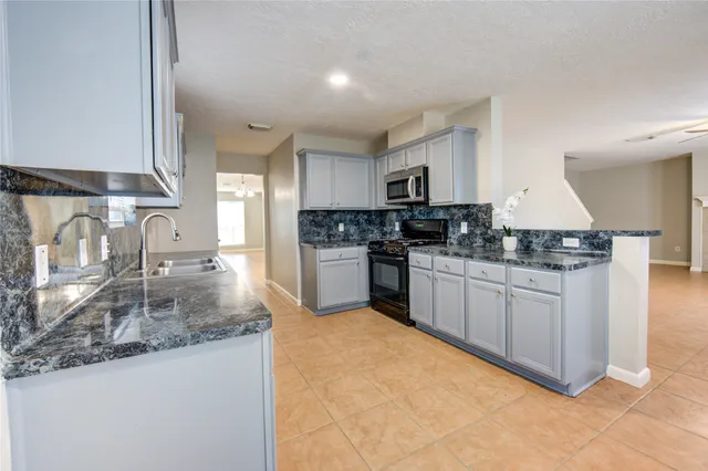 a large kitchen with stainless steel appliances granite countertop a stove a sink dishwasher and a refrigerator