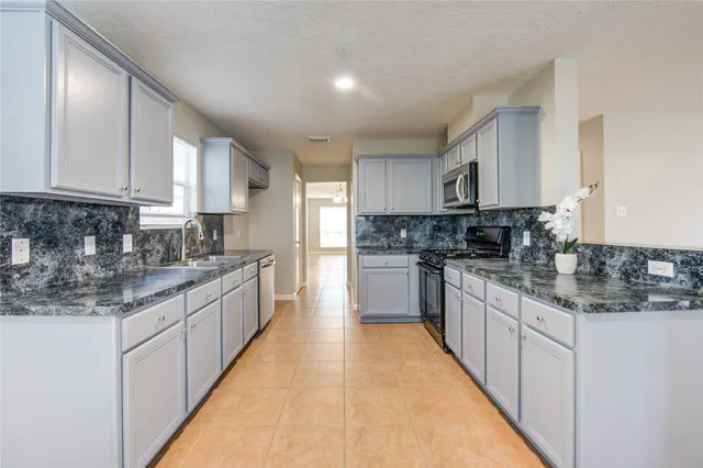 a kitchen with stainless steel appliances granite countertop a sink a stove a refrigerator cabinets and a counter top space