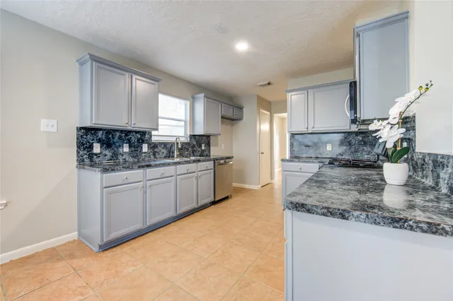 a kitchen with stainless steel appliances a sink a stove a refrigerator cabinets and a kitchen island