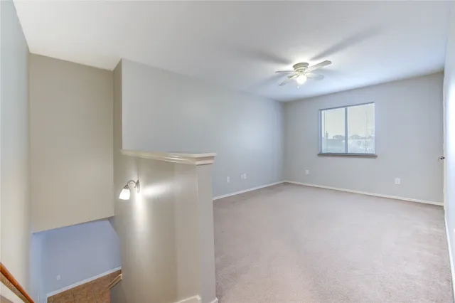 an empty room with a chandelier fan and windows