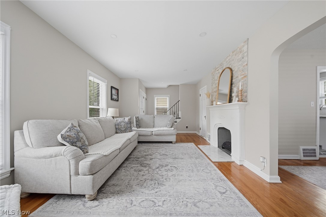 2231 Brockway Road University Heights, OH 44118 - Photo 8 of 46 Spacious living area featuring wood-finish flooring, a white mantel fireplace with a light-toned stone surround, an arched doorway, and multiple windows
