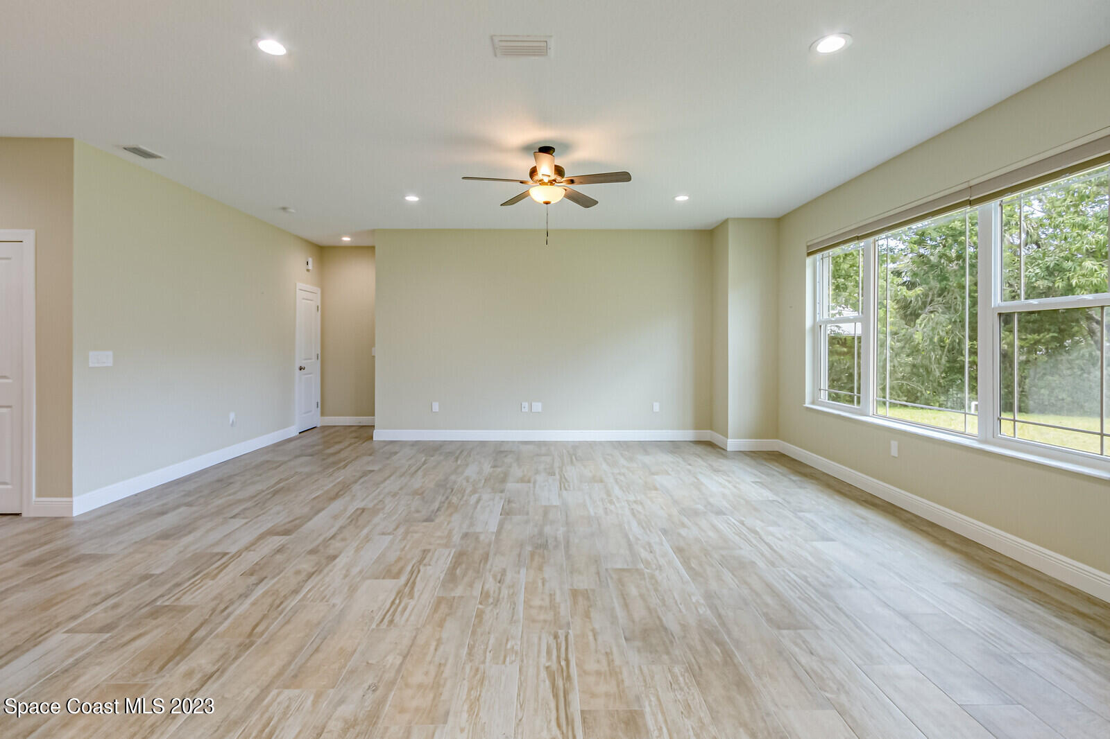 618 Hammock Road Melbourne, FL 32904 - Photo 16 of 59 an empty room with wooden floor chandelier fan and windows