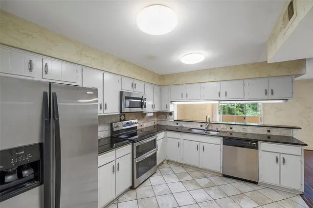 a kitchen with stainless steel appliances granite countertop a refrigerator sink and stove