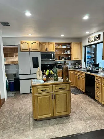 a kitchen with kitchen island a stove a sink a refrigerator and a microwave