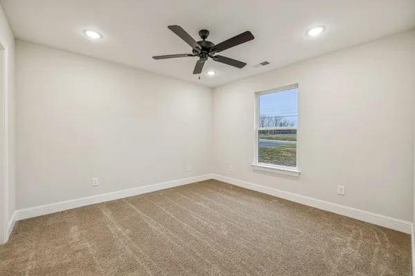 an empty room with ceiling fan and window