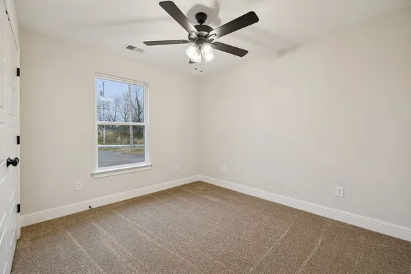 an empty room with a window and a fan