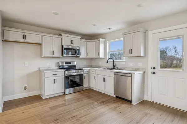 a kitchen with granite countertop white cabinets and stainless steel appliances