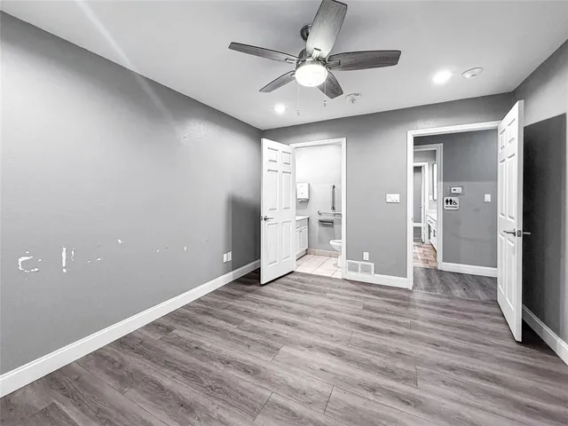 a view of an empty room with wooden floor and a ceiling fan