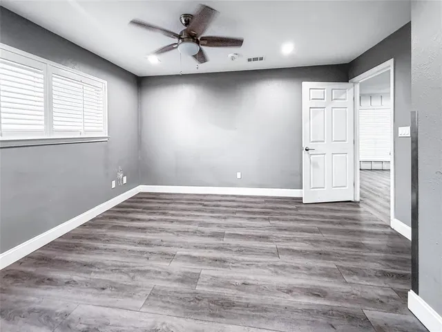 a view of empty room with wooden floor and fan