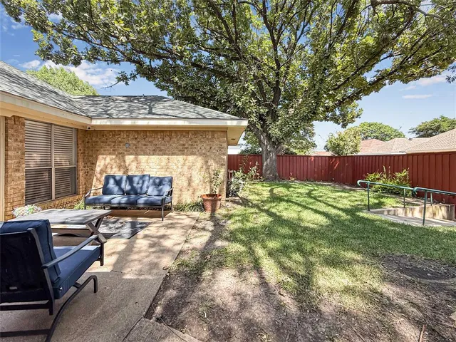 a view of a backyard with table and chairs potted plants and a large tree