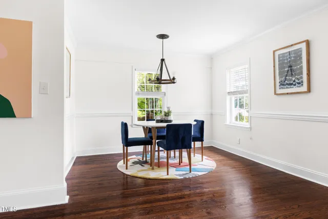 a dining room with wooden floor a chandelier a wooden table and chairs