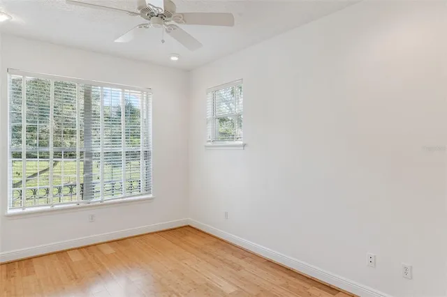 a view of an empty room with a window and wooden floor