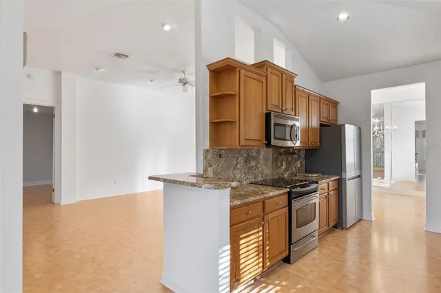 a kitchen with stainless steel appliances granite countertop a refrigerator a stove and a sink