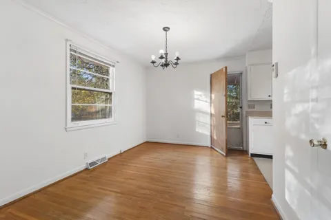 a view of a room with wooden floor a ceiling fan and windows