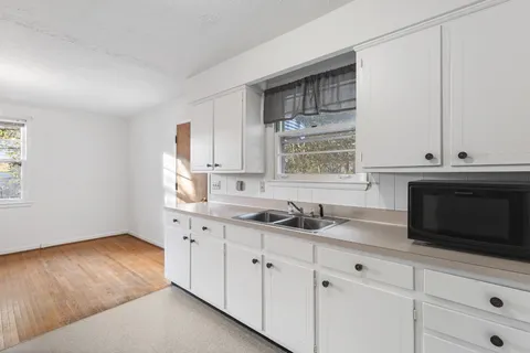 a kitchen with granite countertop white cabinets and a sink