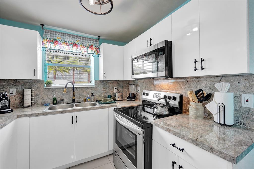 8236 Northwest 1st Place, Unit 2 Miami, FL 33150 - Photo 17 of 21 a kitchen with kitchen island granite countertop a sink a stove and cabinets