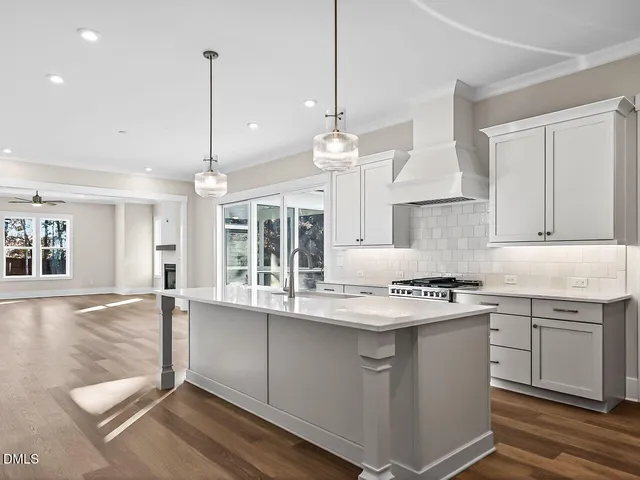 a kitchen with stainless steel appliances granite countertop a stove a sink and white cabinets with wooden floor