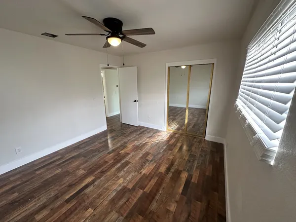 a view of an empty room and window and wooden floor
