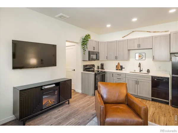 a kitchen with stainless steel appliances kitchen island granite countertop a stove top oven a sink dishwasher a dining table and chairs with wooden floor