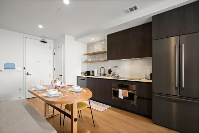 a kitchen with stainless steel appliances wooden floor dining table and chairs