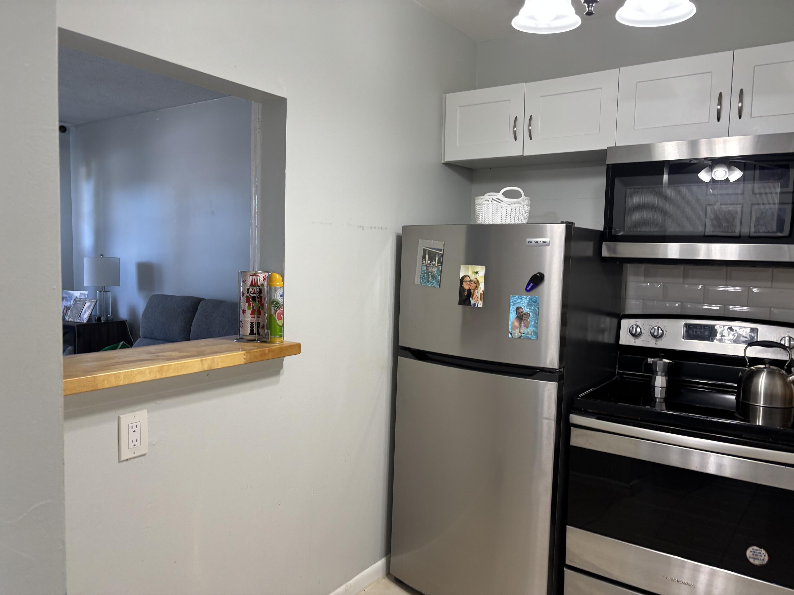 243 Northampton M, Unit 243 West Palm Beach, FL 33417 - Photo 8 of 15 a kitchen with stainless steel appliances a refrigerator a stove and a sink