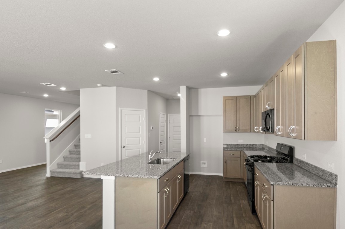 230 Barley Lane Elgin, TX 78621 - Photo 21 of 39 a kitchen with stainless steel appliances kitchen island granite countertop a sink and a refrigerator