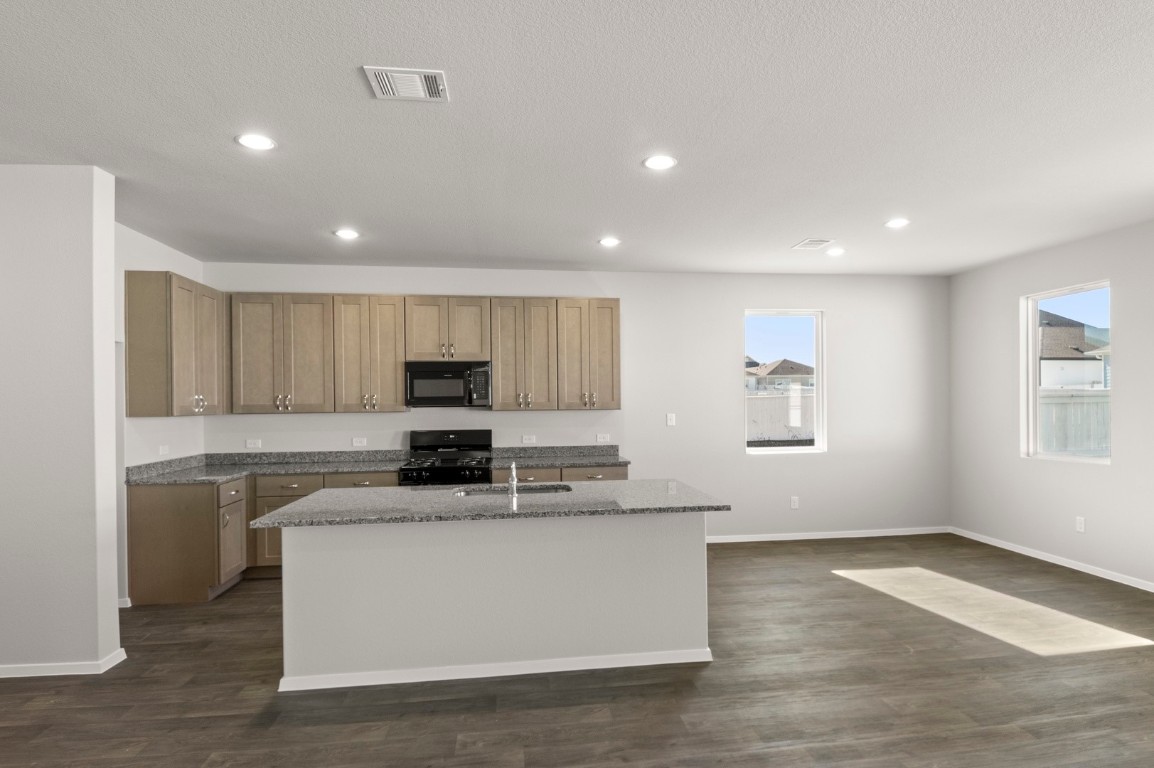 230 Barley Lane Elgin, TX 78621 - Photo 26 of 39 a kitchen with stainless steel appliances granite countertop a stove a sink and a refrigerator