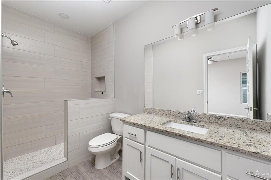 1804 Stauffer Street Weslaco, TX 78596 - Photo 17 of 23 a bathroom with a granite countertop toilet a sink and a mirror
