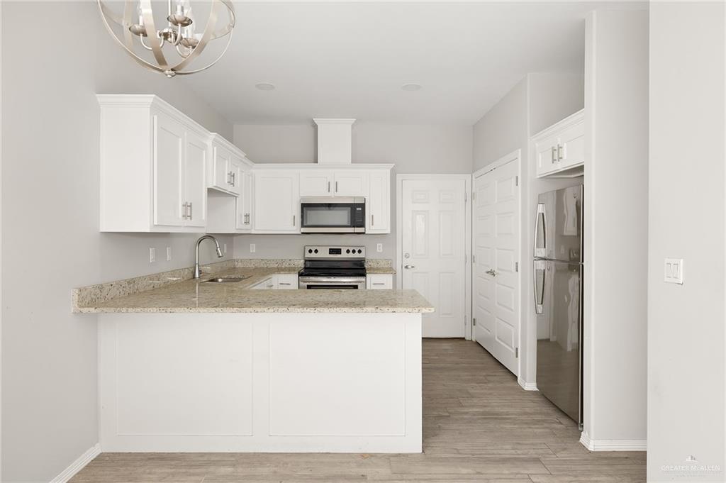 1804 Stauffer Street Weslaco, TX 78596 - Photo 8 of 17 a kitchen with stainless steel appliances granite countertop a sink a stove a refrigerator with white cabinets