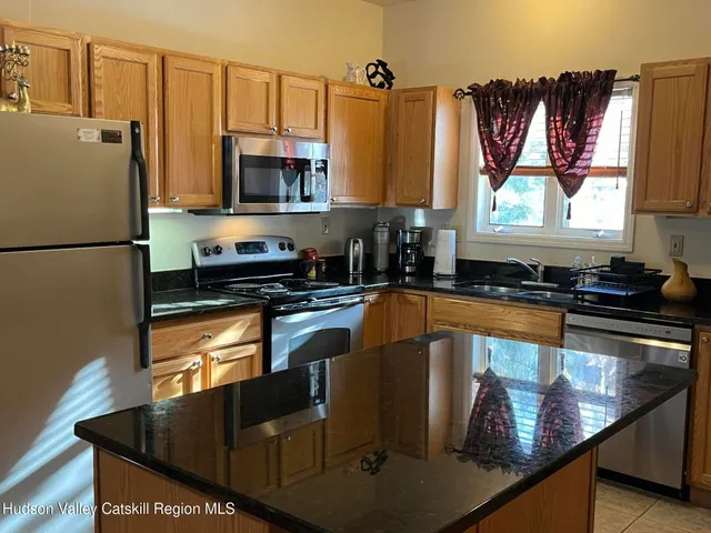 a kitchen with stainless steel appliances granite countertop a refrigerator a stove and a sink with wooden floor